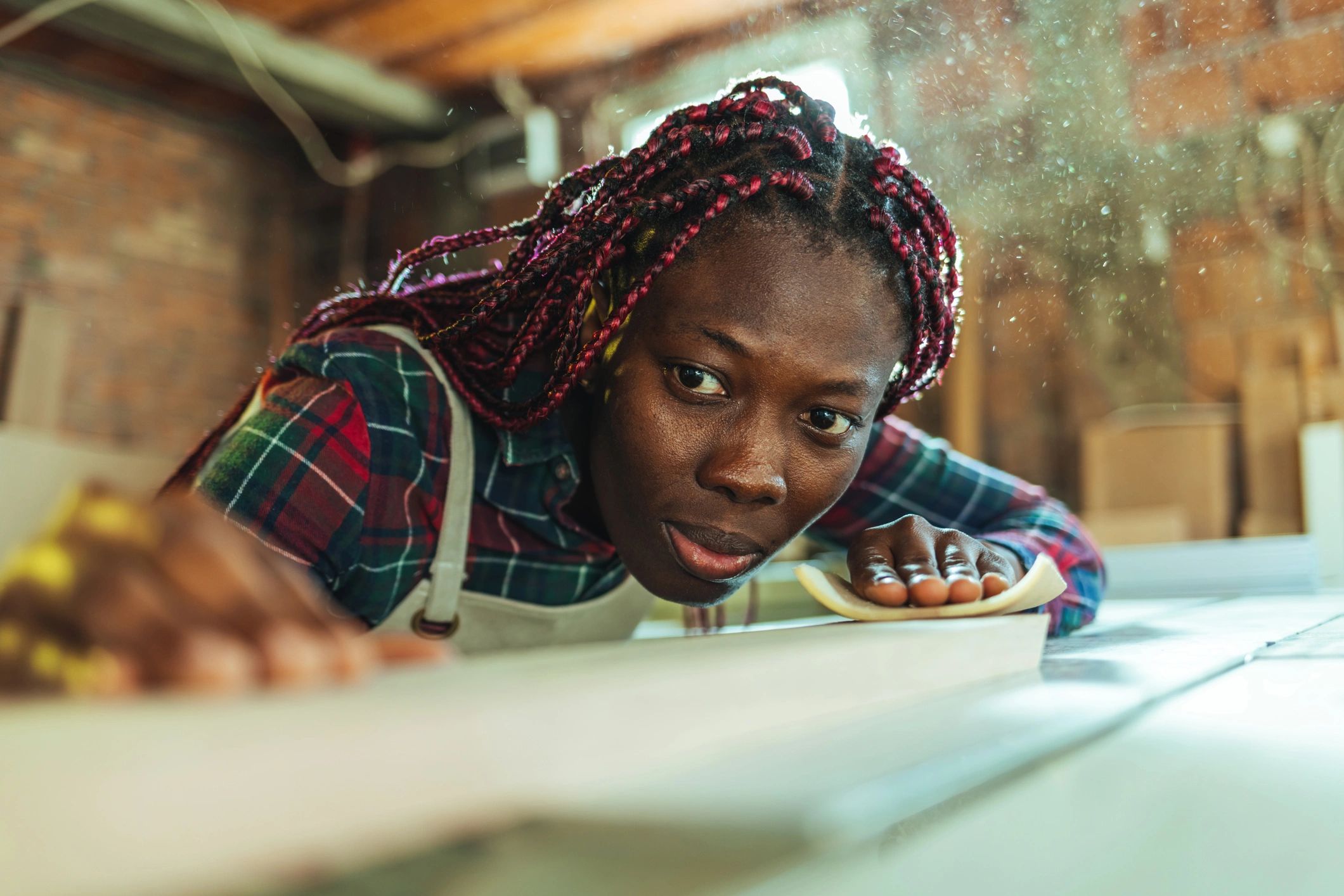 Apprentice carpenter sanding timber in a workshop
