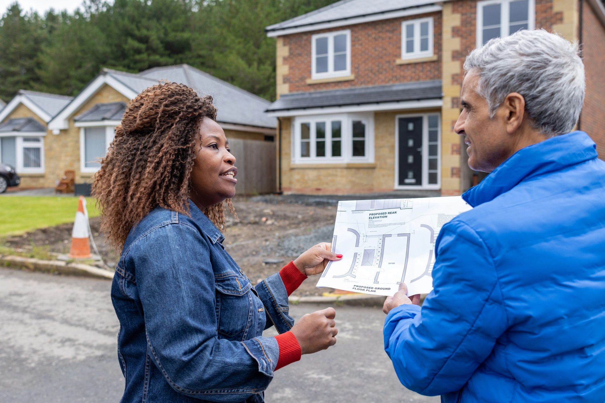 Two professionals reviewing building plans at a housing development site