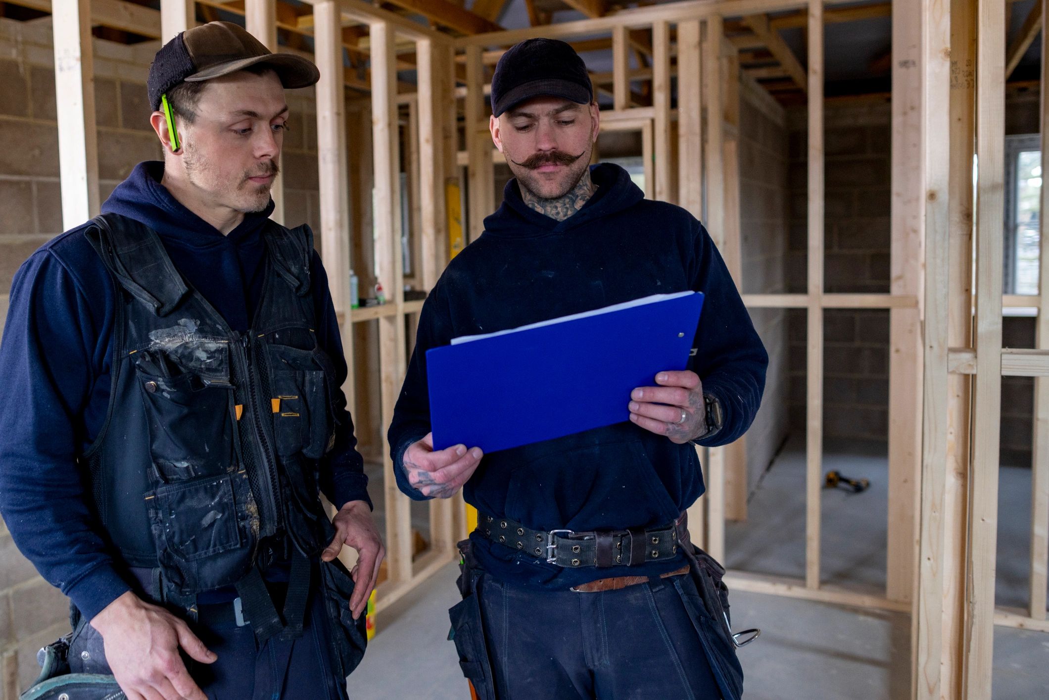 Two builders reviewing construction plans on a residential building site