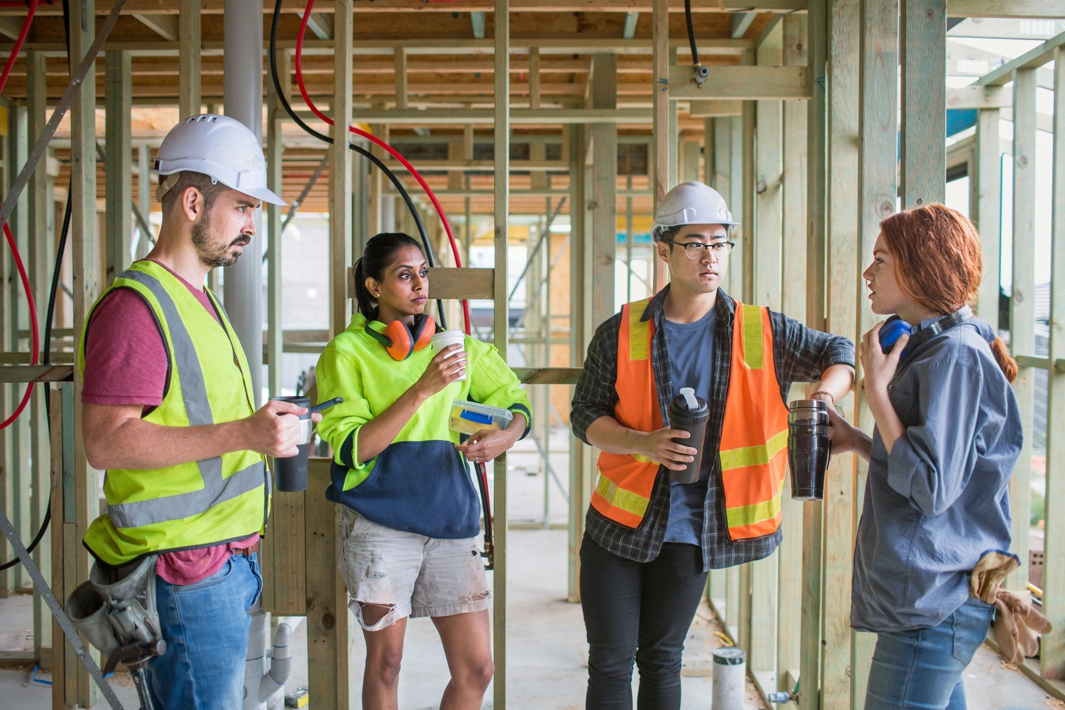 Construction worker speaking with colleagues on a building site over coffee